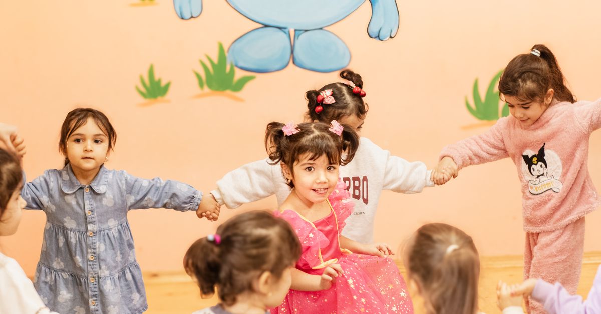 Happy children holding hands in a playful indoor circle game, enjoying a fun activity together.